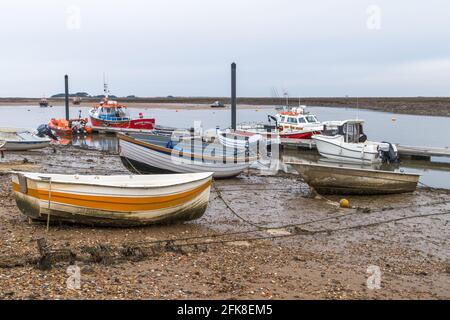 Ruderboote sitzen bei Ebbe auf dem Schlamm, gesehen in Wells-Next-Sea in Norfolk. Stockfoto