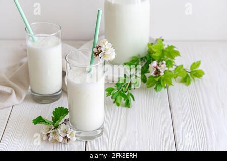 Frisches, natürliches Joghurtgetränk auf weißem Hintergrund. Zwei Gläser Lassi auf grünem Hintergrund. Stockfoto