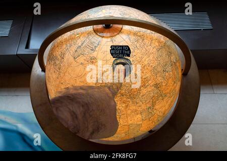 Drücken Sie den Finger der menschlichen Hand, um die Welt wieder in den Griff zu bekommen Details zum alten Erdglobus aus nächster Nähe Stockfoto