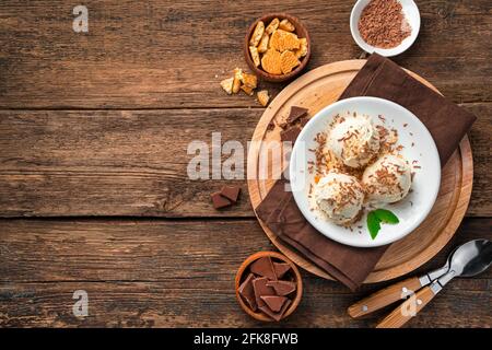 Cremiges Eis mit Schokoladenstückchen und Keksen auf hellbeigem Hintergrund. Stockfoto