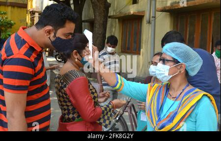 Kalkutta, Indien. April 2021. Ein Stimmarbeiter, der Körpertemperatur mit der Thermopistole misst, bevor er die Abstimmungskabine betreten hat. (Foto: Anubrata Mondal/Pacific Press) Quelle: Pacific Press Media Production Corp./Alamy Live News Stockfoto