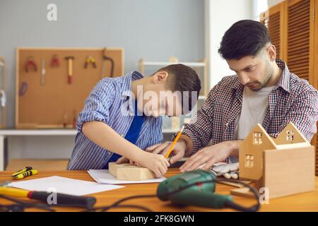 Vater und Sohn bauen hölzerne Vogelhaus verbringen Zeit zusammen an Home Workshop Stockfoto