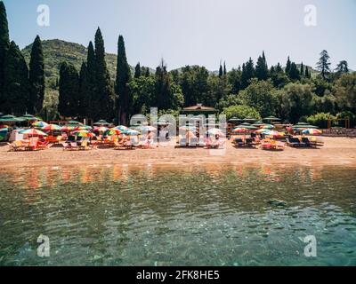 Viele farbige Sonnenschirme am königlichen Strand in Przno dagegen Die Kulisse der grünen Bäume Stockfoto
