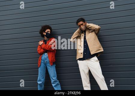 Junges afroamerikanisches Paar in stilvollen Schutzmasken, die draußen posieren Stockfoto