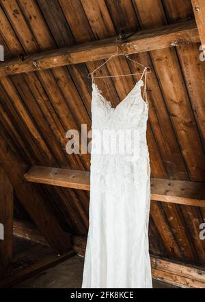 Hochzeitskleid, das im Hotelzimmer von der Decke hängt Sich von der Braut vorbereiten Stockfoto