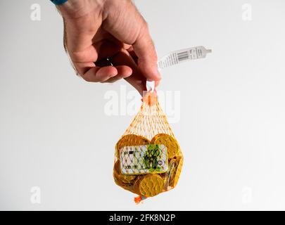 Hält ein Netzpaket mit mehreren Schokoladen-Euro-Münzen Stockfoto