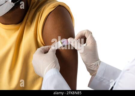Beschnittene Ansicht des Arztes, der Klebstoffputz auf den Arm des afroamerikanischer Patient isoliert auf Weiß Stockfoto