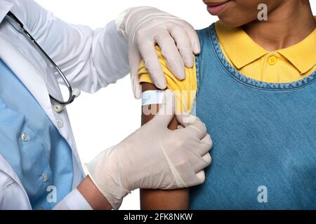 Beschnittene Ansicht des Kinderarztes, der Klebstoff auf den Arm des afroamerikanischer Patient isoliert auf Weiß Stockfoto