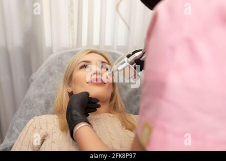 Blonde Frau liegt auf der Couch und erhält Laser-Verjüngungsverfahren. Anti-Aging-Konzept Stockfoto