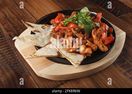 Fajitas mit Huhn und Paprika in einer Pfanne. Holzhintergrund. Stockfoto