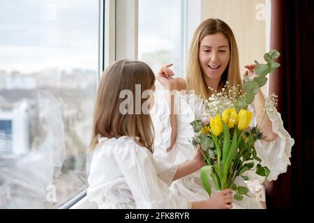 Mutter überraschte mit Blumenstrauß von ihrer Tochter zu Hause Stockfoto