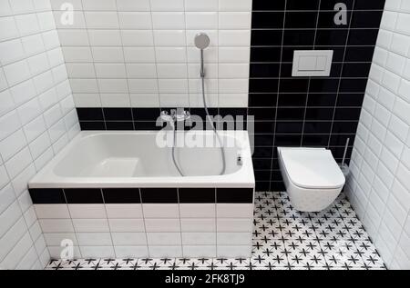 Innenraum des kleinen Badezimmers mit WC, Mini-Badewanne und WC. Keramikwände und -Boden. Stockfoto