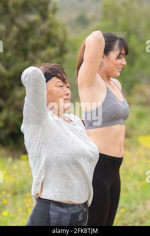 Asiatische Frau Stretching im Freien mit jungen Frau Stockfoto