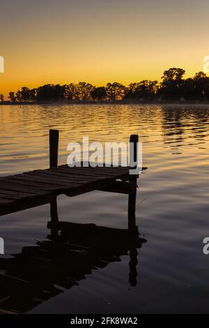 Sonnenuntergang am See Lobos, Buenos Aires. Vom Ufer aus mit Blick auf einen alten, kurzen hölzernen Pier und den See Stockfoto