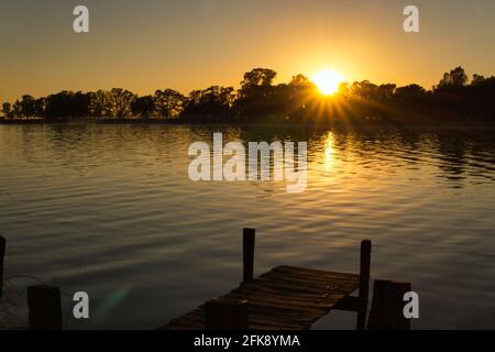 Sonnenuntergang am See Lobos, Buenos Aires. Vom Ufer aus mit Blick auf einen alten, kurzen hölzernen Pier und den See Stockfoto