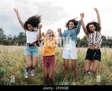 Gruppe von verschiedenen Frauen, die im Freien zusammen springen. Freunde, die Spaß im Urlaub haben. Stockfoto