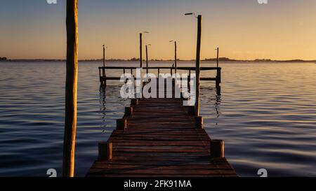 Sonnenuntergang am See Lobos, Buenos Aires. Vom Ufer aus mit Blick auf einen alten, großen Holzsteg und den See Stockfoto