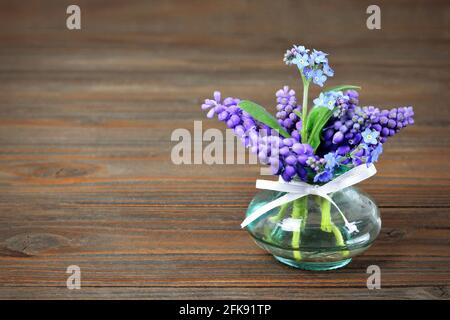 Vergiss mich nicht und Muscari blüht in Vase auf Holz Hintergrund Stockfoto