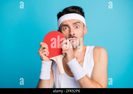 Foto von jungen sportlichen Mann halten Tennisschläger Angst Spielen Sie Tennis isoliert auf blauem Hintergrund Stockfoto