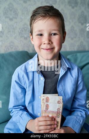 Der Junge hält ein Paket russischer 5.000-Dollar-Scheine in sich Seine Hände Stockfoto