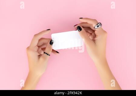 Womans Hand mit trendigen Maniküre halten Visitenkarte auf rosa Hintergrund Stockfoto