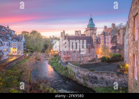 Lebhafter, farbenfroher Sonnenuntergang oder Sonnenaufgangshimmel über der historischen Architektur des Dean Village am Wasser von Leith in Edinburgh, Schottland. Stockfoto