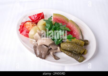 Köstliches mariniertes Gemüse. Teller auf einem weißen Leinwandtischtuch Hintergrund. Stockfoto