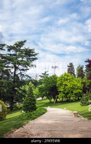 Pfad im Parque del Oeste Park in Madrid, mit dem Übertragungsturm Faro de Moncloa im Hintergrund. Stockfoto