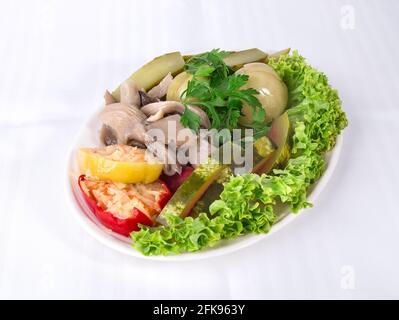 Köstliches mariniertes Gemüse. Teller auf einem weißen Leinwandtischtuch Hintergrund. Stockfoto