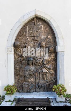 Holztür mit einem Bronzerelief bedeckt, St. Nikolaus Kathedrale in Novo mesto, Slowenien Stockfoto