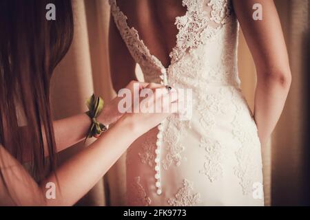 Wunderschöne, Braut in weißem Kleid, die Vorbereitung für die Hochzeit. Frau zieht sich ein Kleid an. Stockfoto