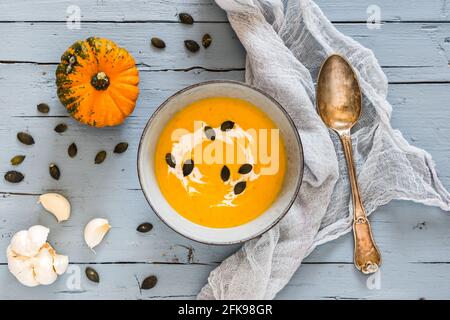 Schüssel mit Kürbissuppe auf hellblauem rustikalem Holzhintergrund, Draufsicht Stockfoto