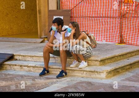 Pienza, Italien, 6. September 2020. 2 maskierte Touristen hören während der COVID-19-Pandemie auf der Piazza Pio II, Pienza, Toskana, Italien, einem Audioguide zu Stockfoto