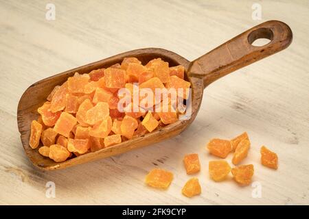 Getrocknete Mangofrucht gewürfelt - rustikale Holzlöffel auf einem Verzweifelter Holzhintergrund Stockfoto