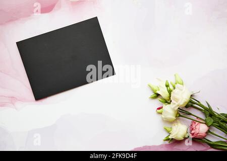 Stiller Sommer Schreibwaren Stillleben auf rosa fließende Oberfläche. Rosa und weiße Eustona-Blüten. Leere Grußkarte – Nachbau der Szene. Stockfoto