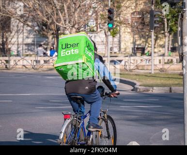 Bukarest, Rumänien - 03.17.2021: Uber isst Kurier auf einem Fahrrad mit der grünen Liefertasche. Junger Erwachsener, der die Bestellung ausliefert Stockfoto