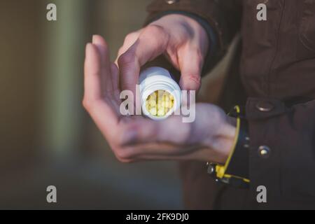 Menschliche Hand hält gelbe Pillen im Freien. Prävention der Ausbreitung von Viren und Pandemie COVID-19. Pillen für Viruserkrankungen. Stockfoto