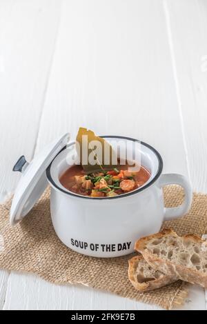 Schüssel mit Soljanka, einer würzigen und sauren Suppe russischen Ursprungs, auf weißem Holztisch. Soljanka ist in den osteuropäischen Ländern und in Ostdeutschland beliebt. V Stockfoto