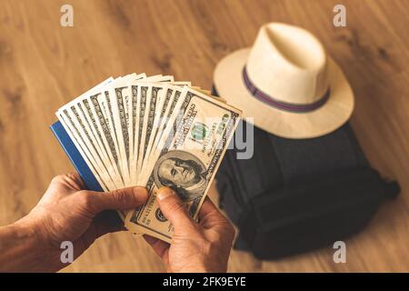Reisende halten Geld auf dem Hintergrund der Tasche und Strohhut, teure Reise-Konzept, Haufen US-Dollar in den Händen Stockfoto