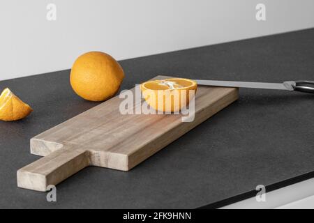 In Scheiben geschnittene Orangen auf einem Holzschneidebrett mit Messer Stockfoto