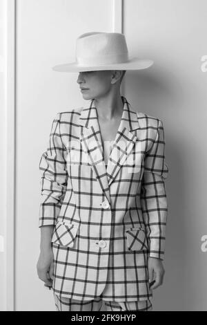 Elegante und charismatische blonde und kurzhaarige Frauen mit einem schönen breiten Lächeln in einem übergroßen Leinenanzug, der isoliert im Studio posiert. Schwarz und Weiß Stockfoto