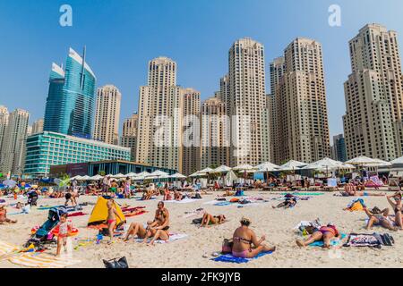 DUBAI, VAE - 21. OKTOBER 2016: Menschen am Marina Beach in Dubai, Vereinigte Arabische Emirate. Jumeirah Beach Residence Komplex im Hintergrund. Stockfoto