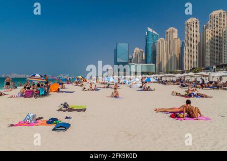 DUBAI, VAE - 21. OKTOBER 2016: Menschen am Marina Beach in Dubai, Vereinigte Arabische Emirate. Jumeirah Beach Residence Komplex im Hintergrund. Stockfoto