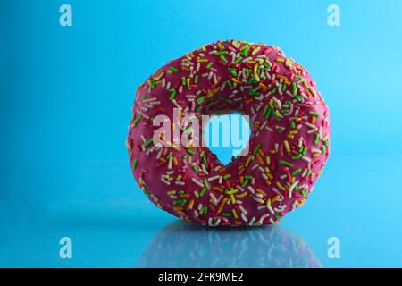 Berliner Donut rosa Schokolade liegt auf einem blauen hellen Hintergrund mit einem Ort, um eine Kopie des Stillleben Frühstück Mahlzeit Text. Stockfoto