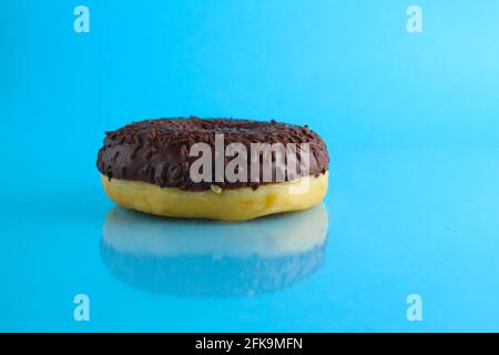 Berliner Donut rosa Schokolade liegt auf einem blauen hellen Hintergrund mit einem Ort, um eine Kopie des Stillleben Frühstück Mahlzeit Text. Stockfoto