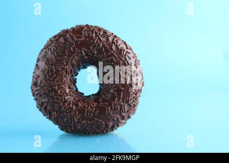 Berliner Donut rosa Schokolade liegt auf einem blauen hellen Hintergrund mit einem Ort, um eine Kopie des Stillleben Frühstück Mahlzeit Text. Stockfoto