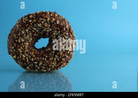 Berliner Donut rosa Schokolade liegt auf einem blauen hellen Hintergrund mit einem Ort, um eine Kopie des Stillleben Frühstück Mahlzeit Text. Stockfoto