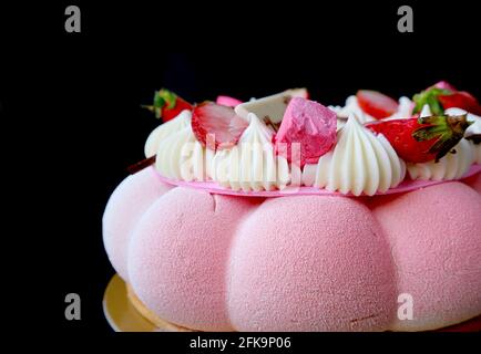 Nahaufnahme eines Pastell Pink Strawberry Mousse Cake isoliert auf Schwarz Hintergrund Stockfoto