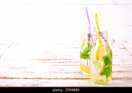 Eiskalte Lavendellimonade, Zitrone, Stroh. Zwei klassische Mojito-Drinks, alkoholfreier Cocktail mit Eis in zwei Vintage-Hipster-Flaschen, auf grunged Stockfoto