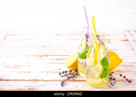 Eiskalte Lavendellimonade, Zitrone, Stroh. Zwei klassische Mojito-Drinks, alkoholfreier Cocktail mit Eis in zwei Vintage-Hipster-Flaschen, auf grunged Stockfoto